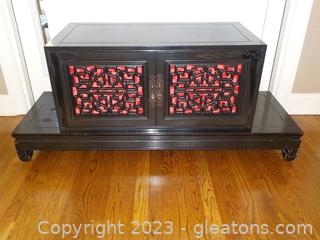 Distinctive Dark Wooden Asian Cabinet on Base with Red Satin Accent Behind Nice Pattern on Doors