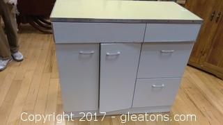 METAL CABINET WITH TWO DRAWERS UP TOP AND TWO ON SIDE WITH DOORS ON ONE SIDE WITH SHELF BEHIND